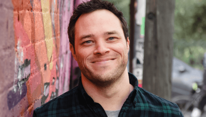 Man leaning against a graffiti wall