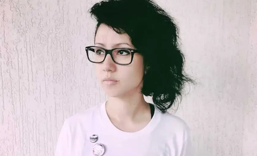 Professional Kara Thattanakham looks off into distance against a cement wall.
